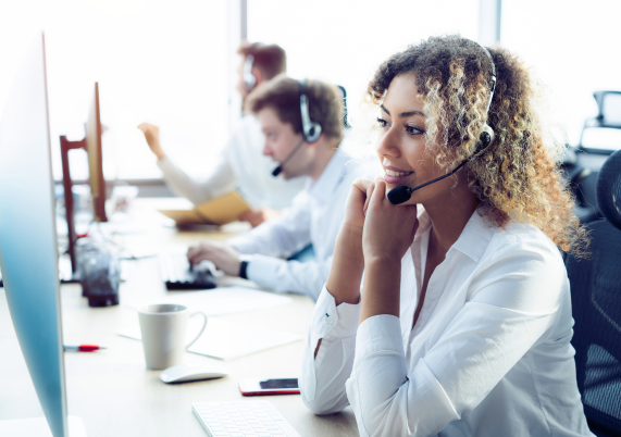 People at their workstation using a headset to call